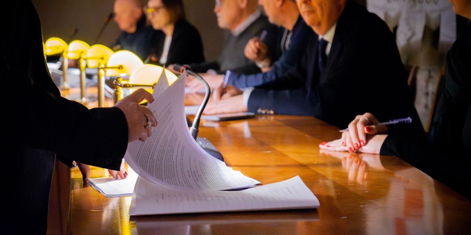 Close-up of a business meeting table with documents being reviewed and signed in Bergamo, Italy.