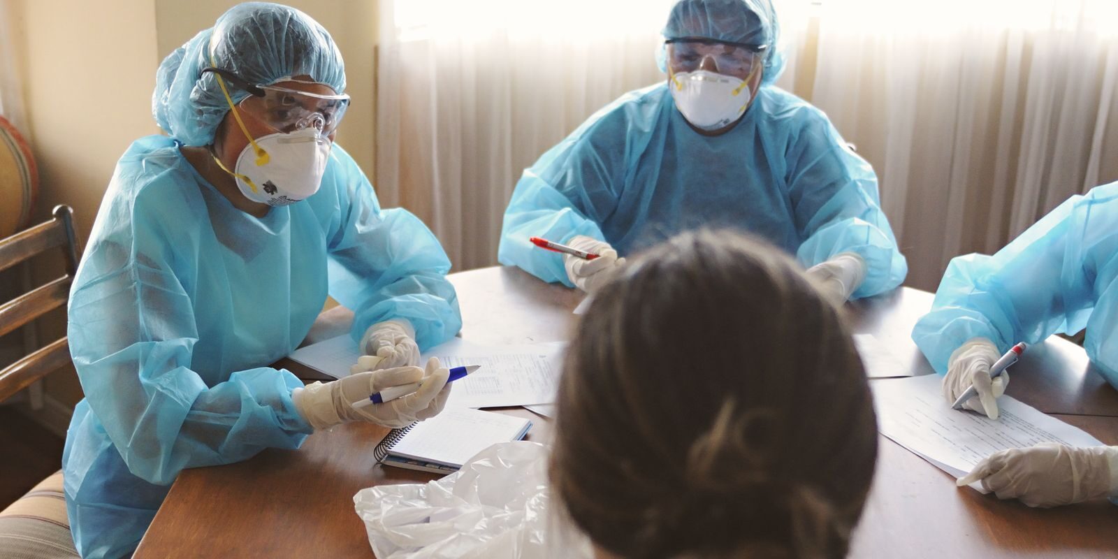 Healthcare professionals in PPE discuss operations during a meeting indoors.