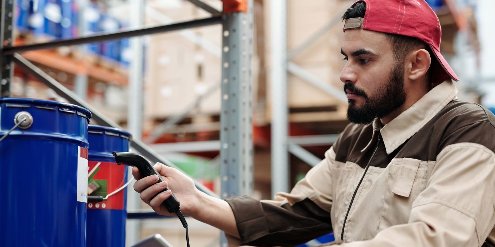 Male warehouse worker scanning barrels with a tablet for inventory management.