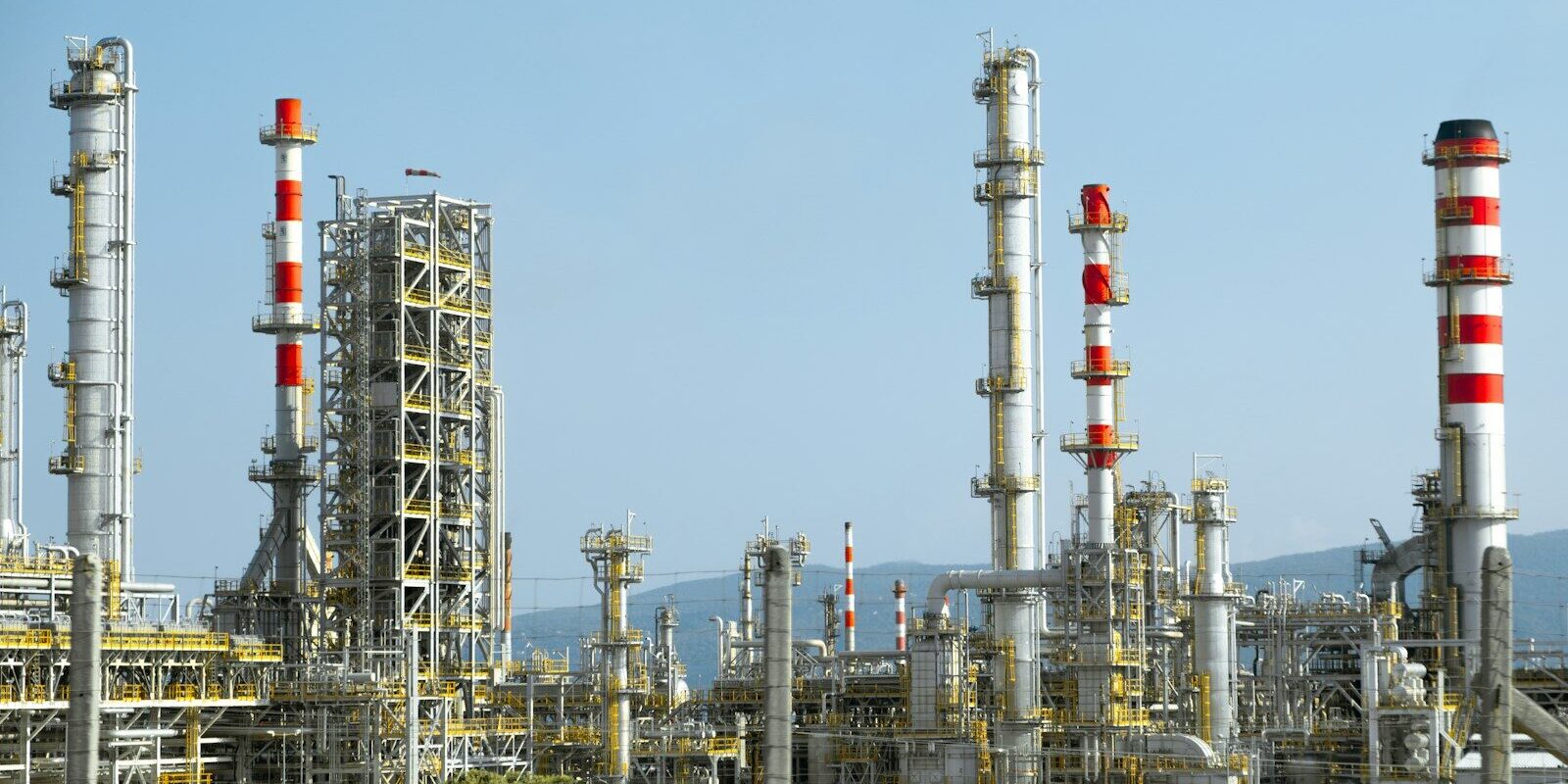 Photo by Christian Harb A factory with a lot of red and white pipes