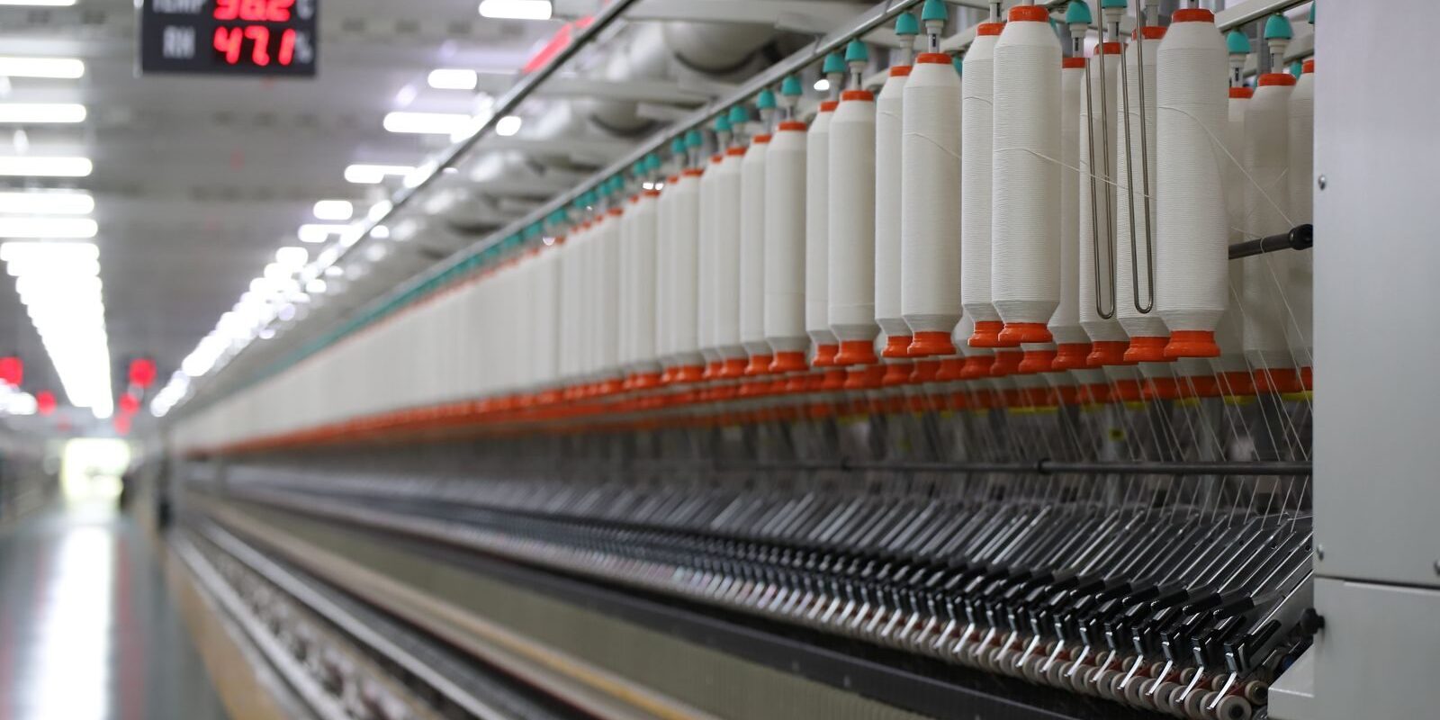 High-tech textile machinery with yarn spools in an Indian factory, demonstrating efficiency.