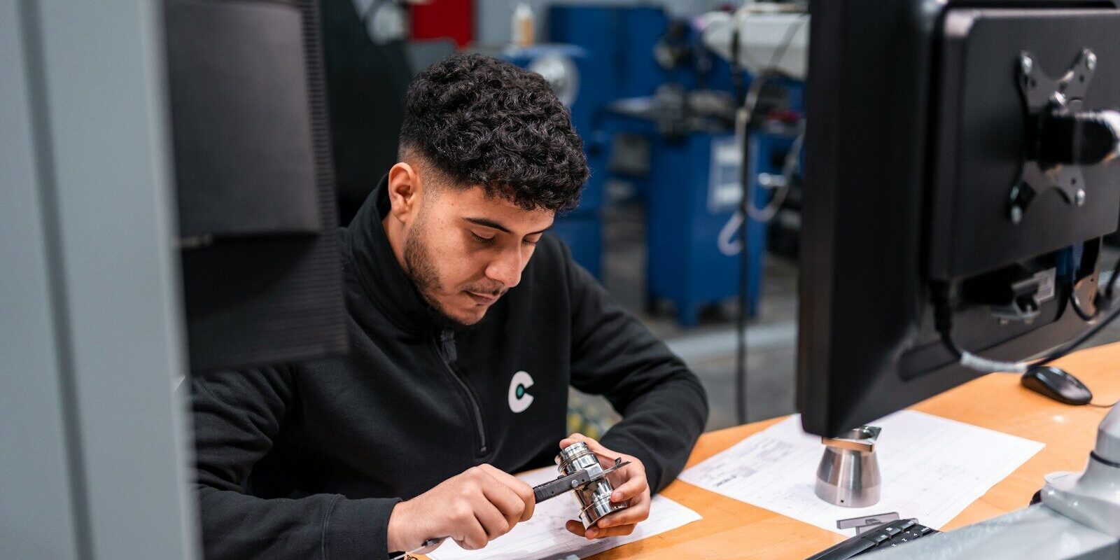 A man measures a metal component carefully