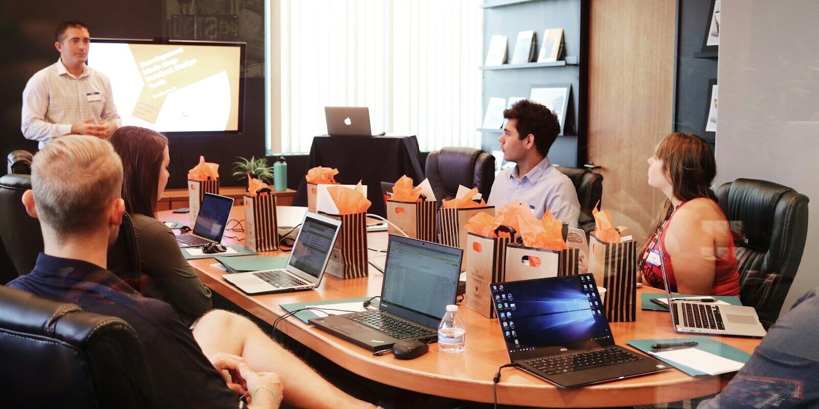 man standing in front of people sitting beside table with laptop computers