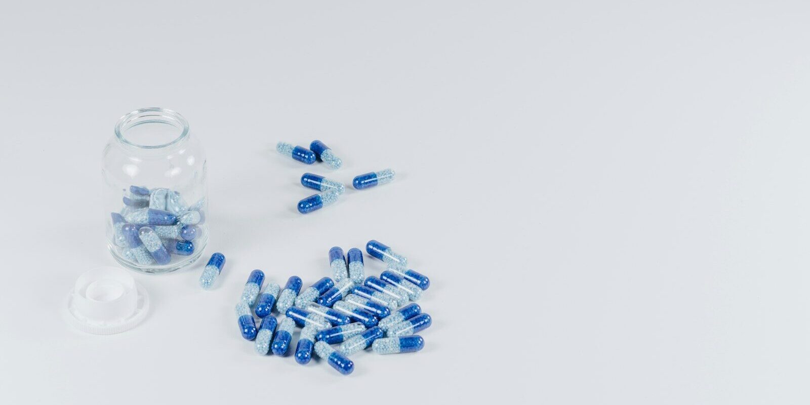 white-and-gray pills beside jar with pills