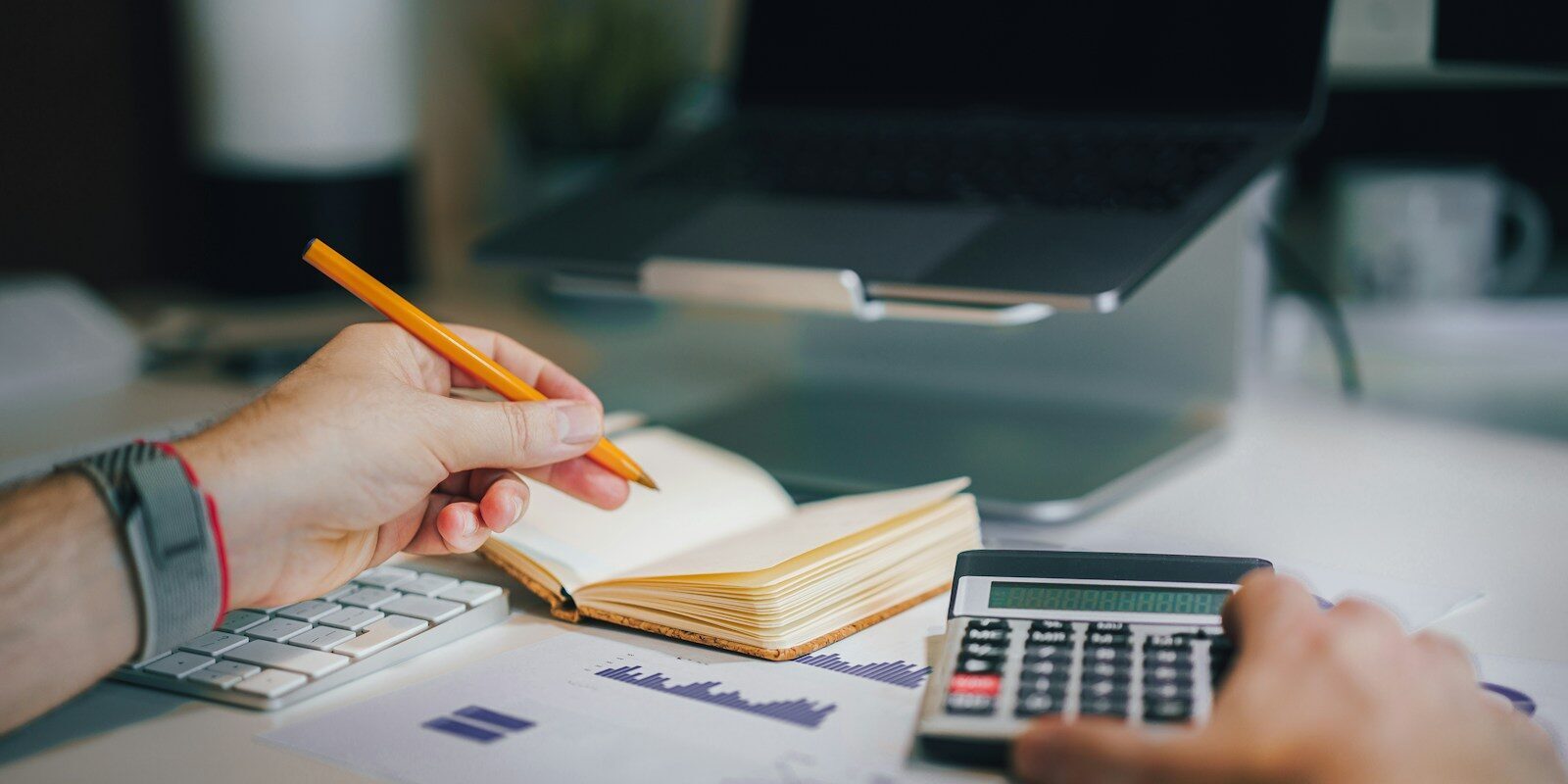 a person sitting at a desk with a calculator and a notebook