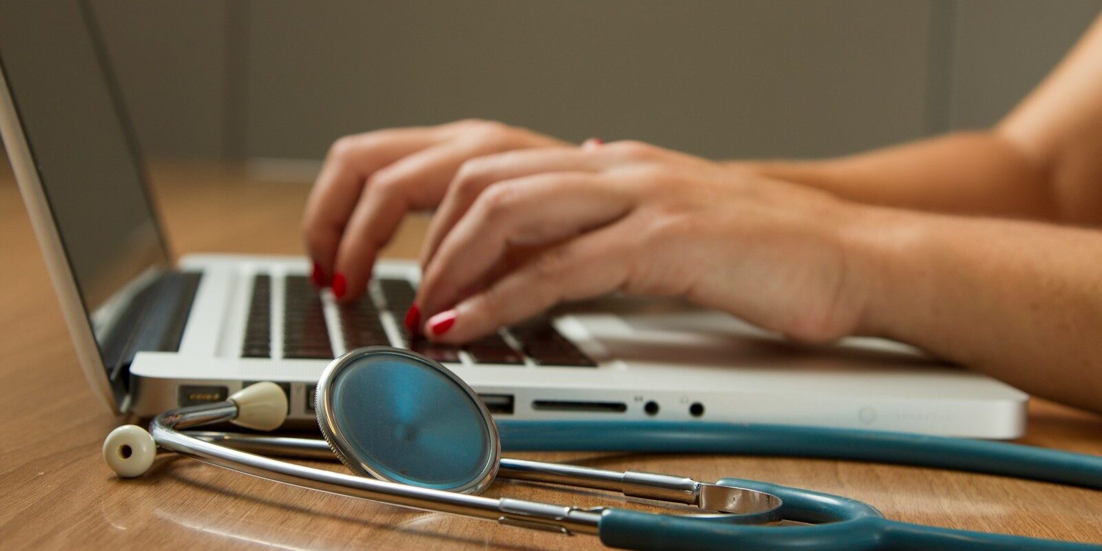 person sitting while using laptop computer and green stethoscope near