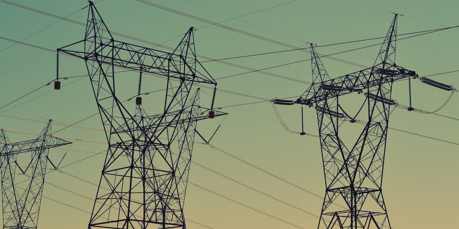 black transmission towers under green sky