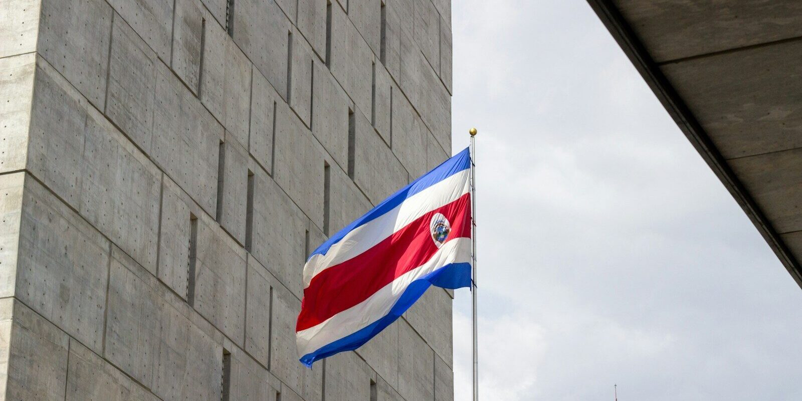 Photo by Sebastian Alvarado Rojas The costa rican flag flies proudly beside a modern building