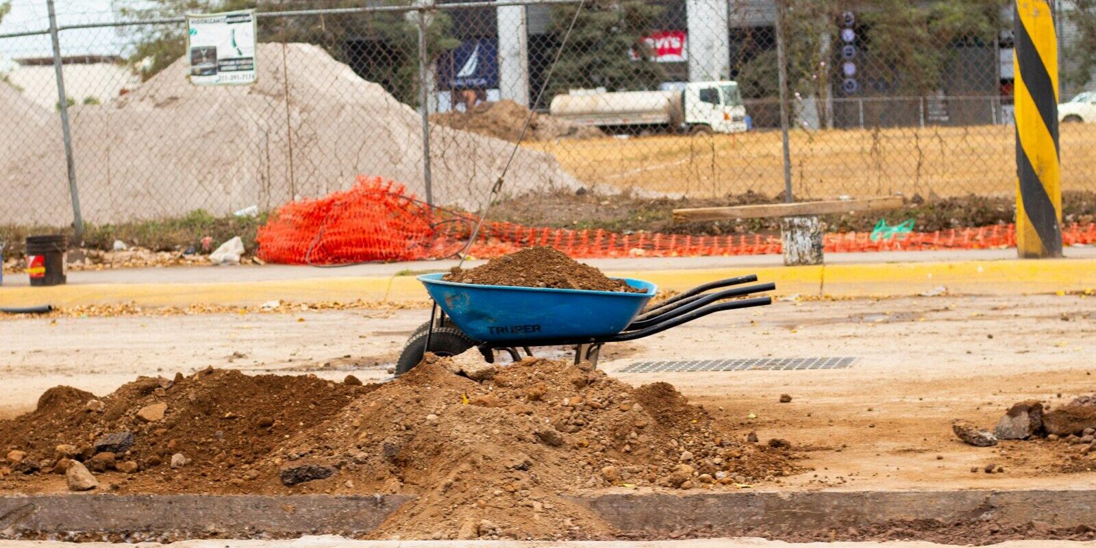 a blue wheelbarrow filled with dirt on a construction site