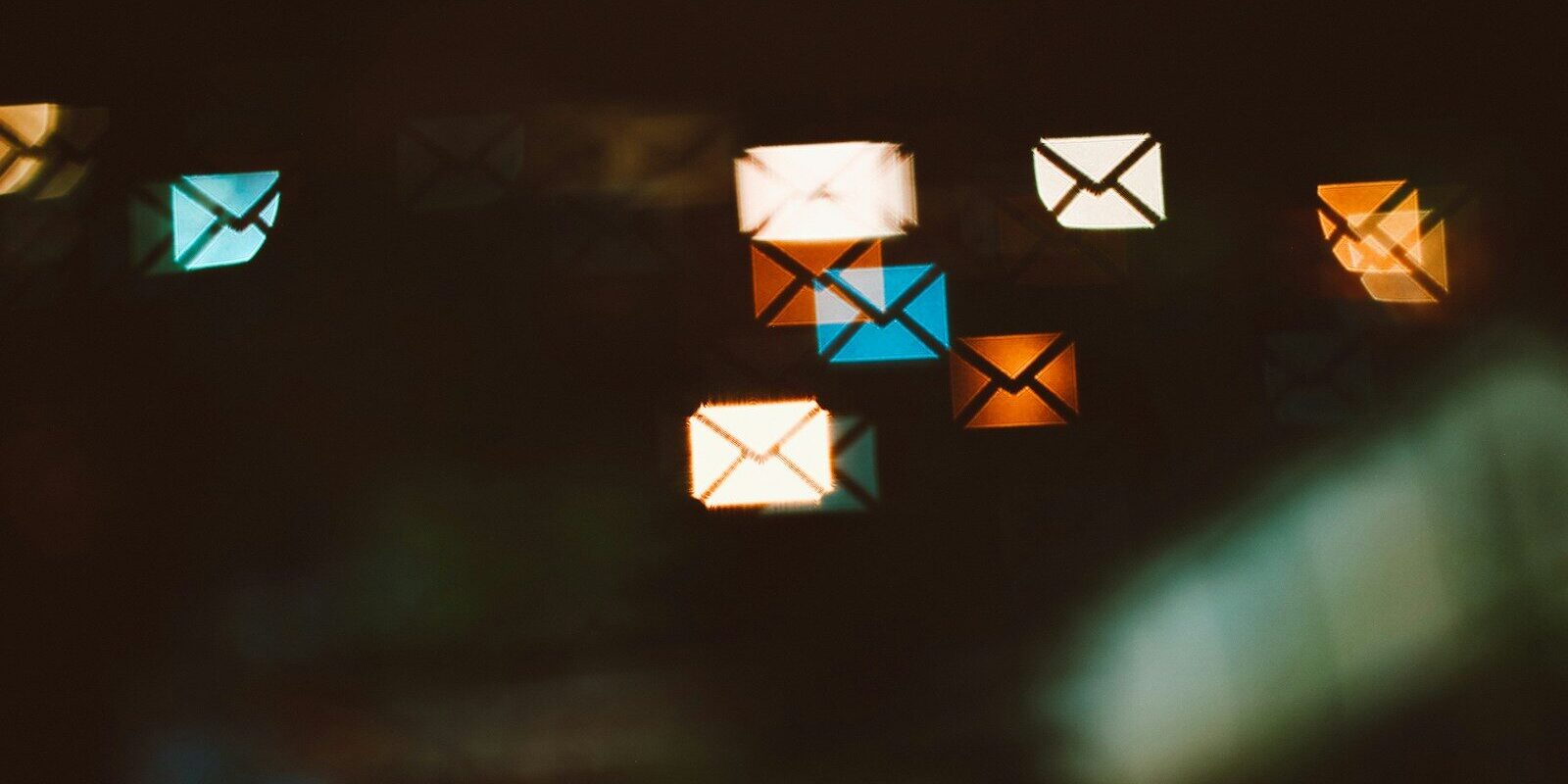 Envelope shaped bokeh lights in blue, orange, and white against a dark background