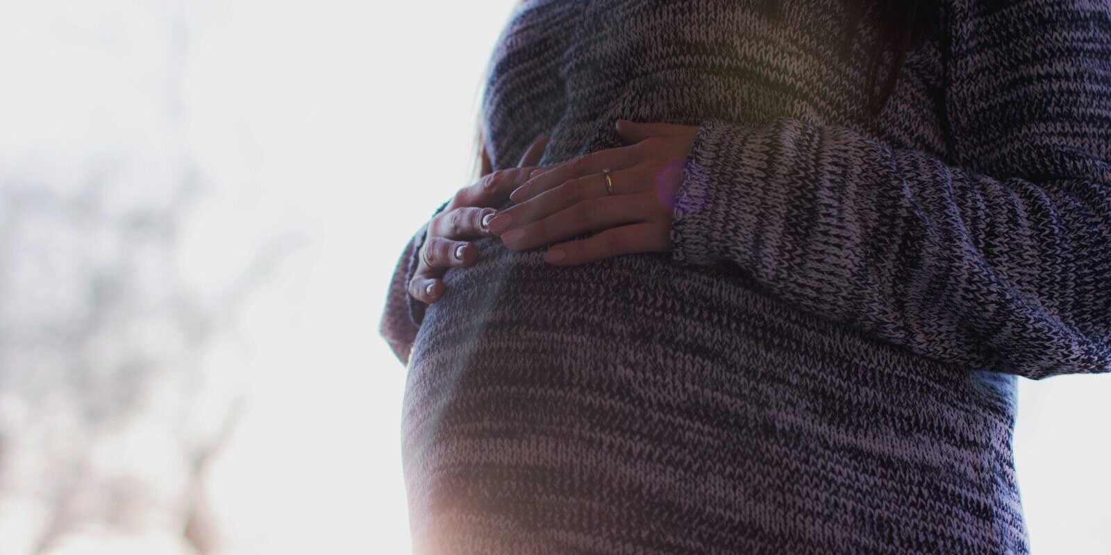 woman holding her prenant tummy during daytime