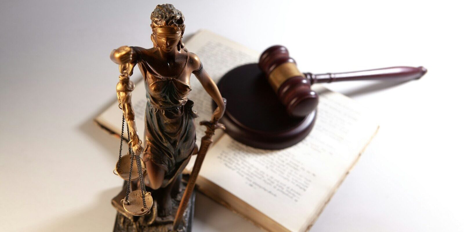 Statue of justice, gavel, and open book on table